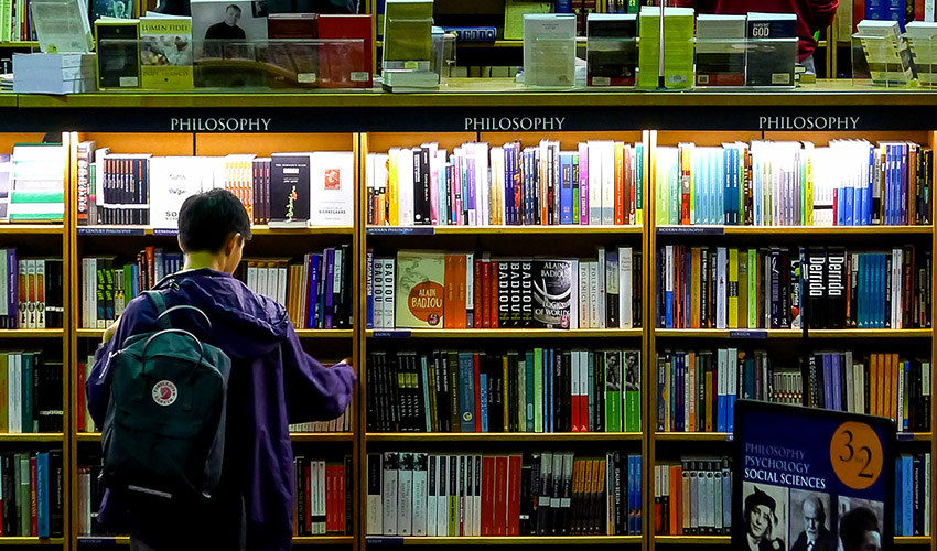 A student ponders a shelf full of textbooks.